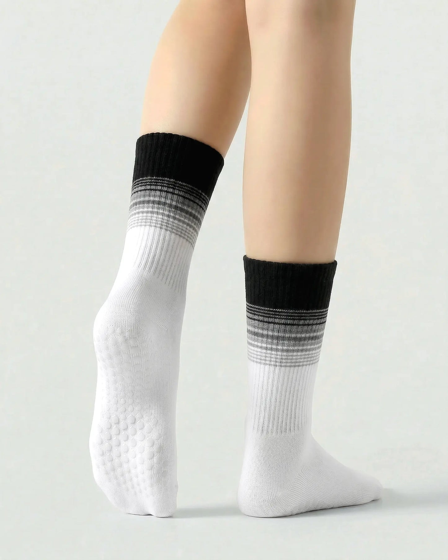 black-white | 02 | Crew grip socks tiptoe standing view showing black-white gradient striping, ribbed structure, and full sole grip coverage