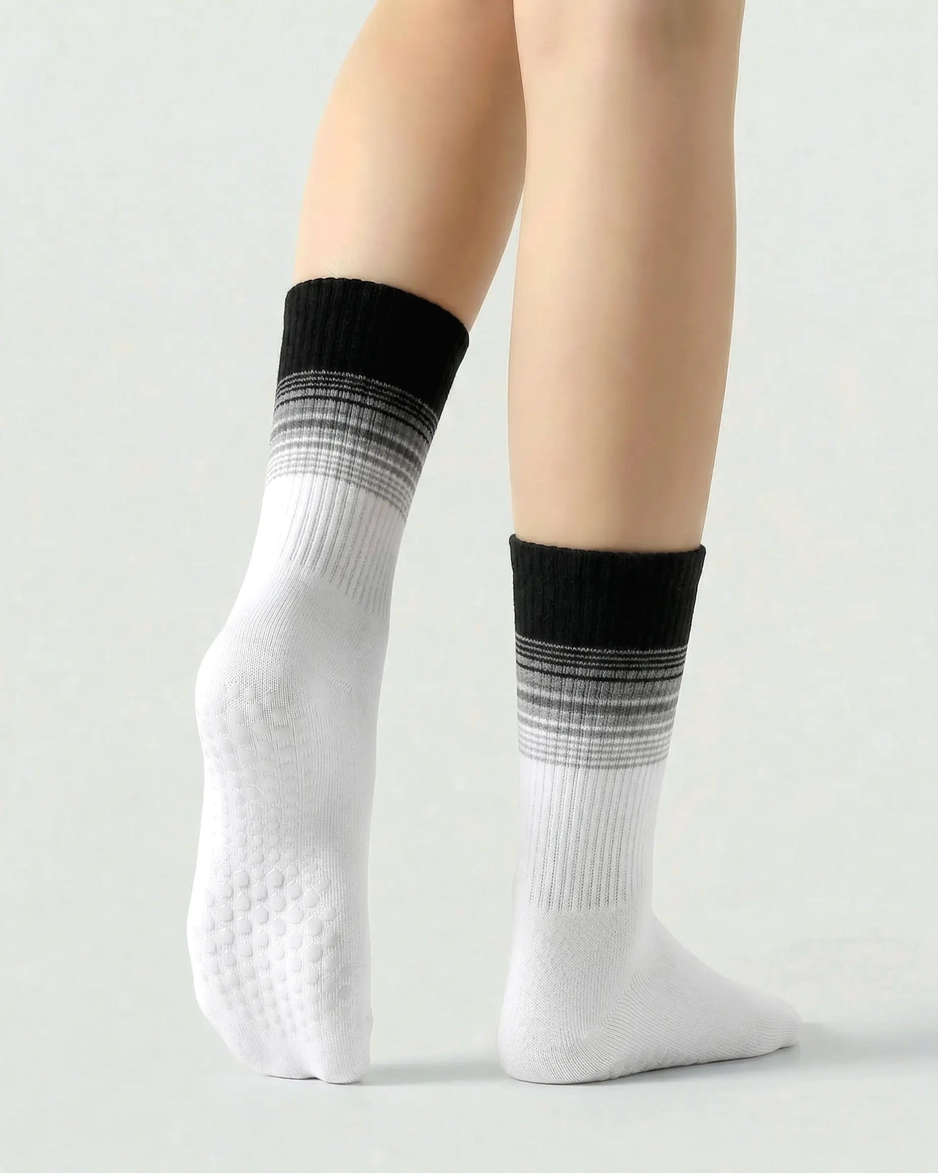black-white | 02 | Crew grip socks tiptoe standing view showing black-white gradient striping, ribbed structure, and full sole grip coverage