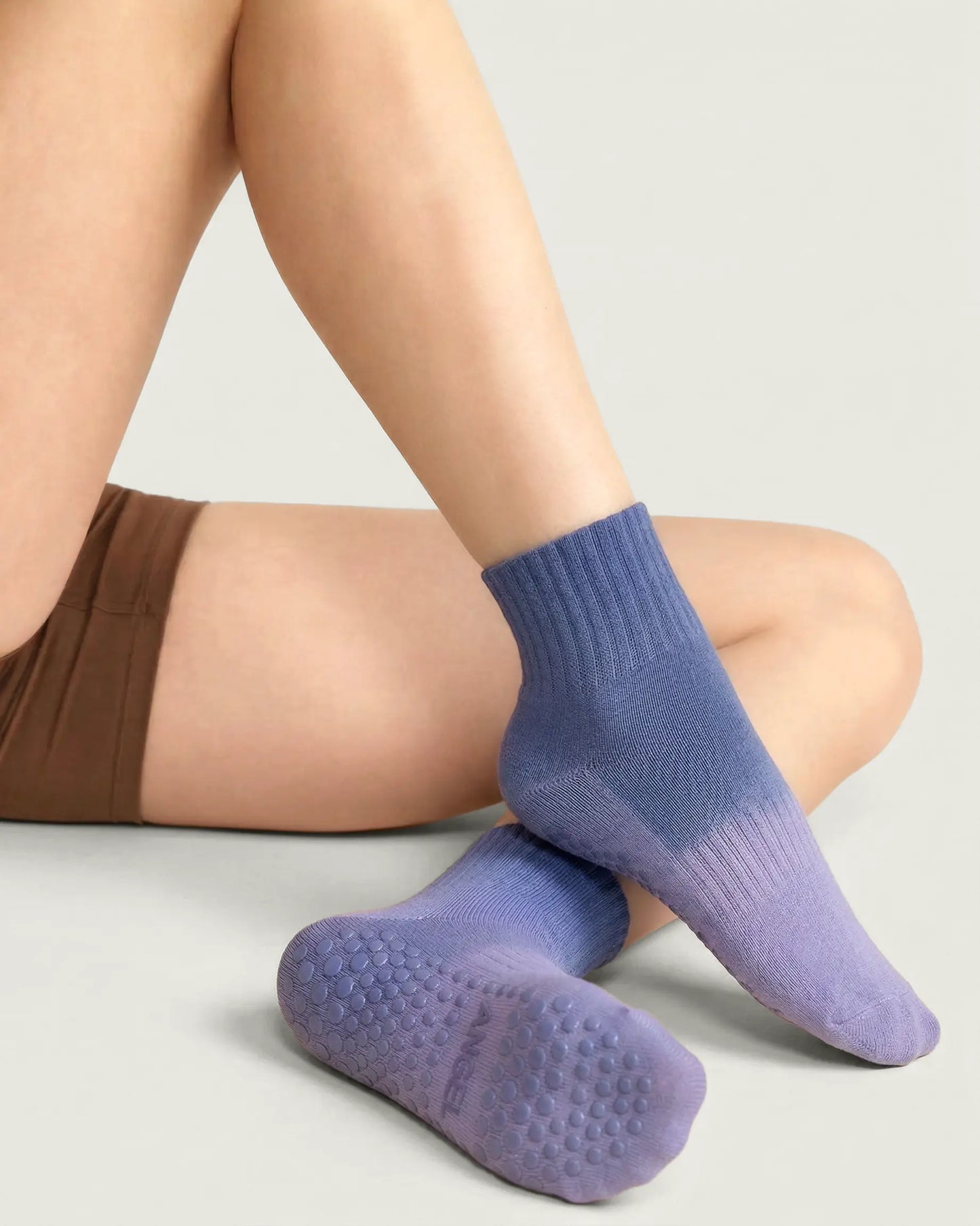 blue-purple | 04 | Blue purple gradient mid-crew grip socks lifestyle seated view showing soft knit texture, gradient color fade, and full sole grip detail