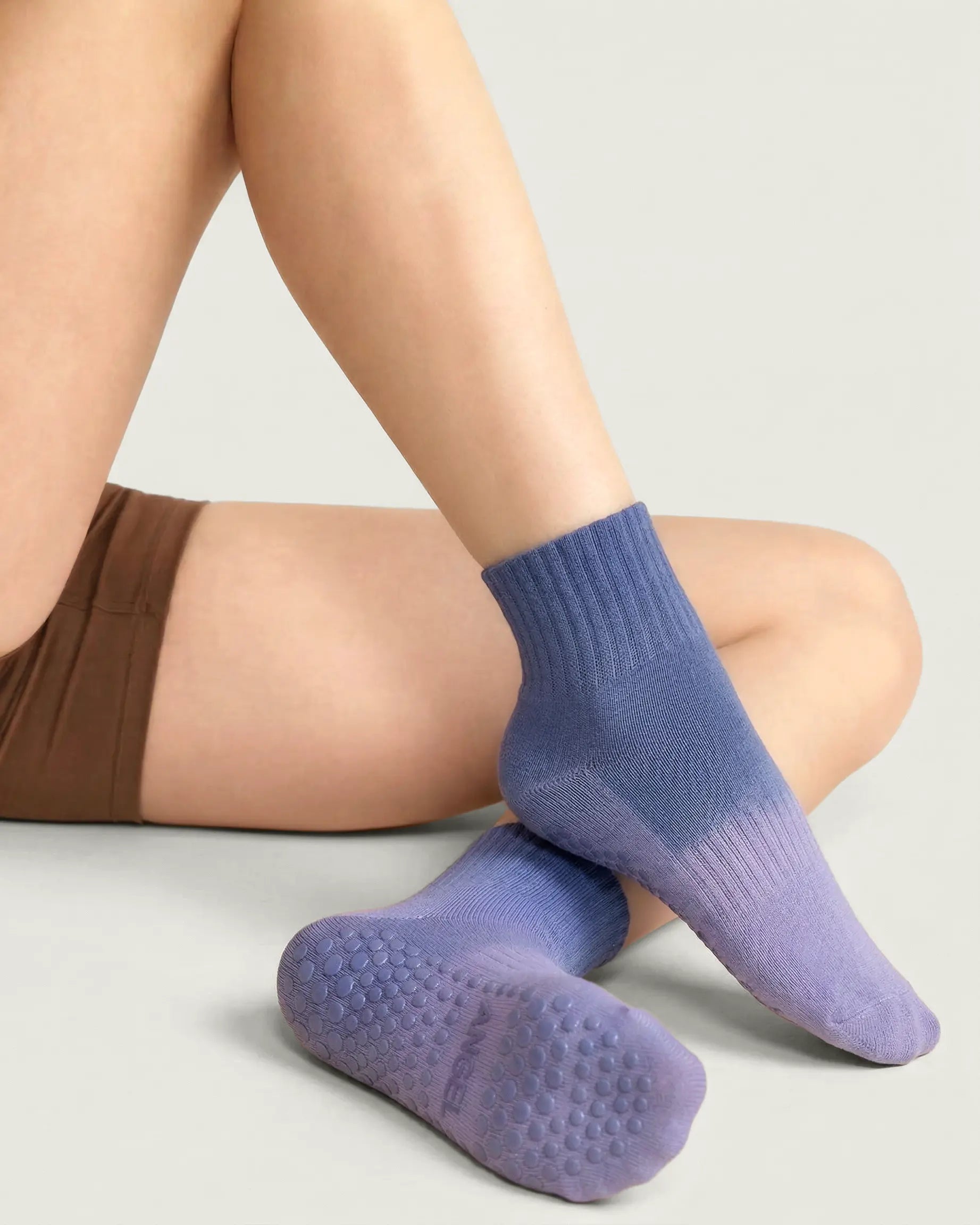 blue-purple | 04 | Blue purple gradient mid-crew grip socks lifestyle seated view showing soft knit texture, gradient color fade, and full sole grip detail