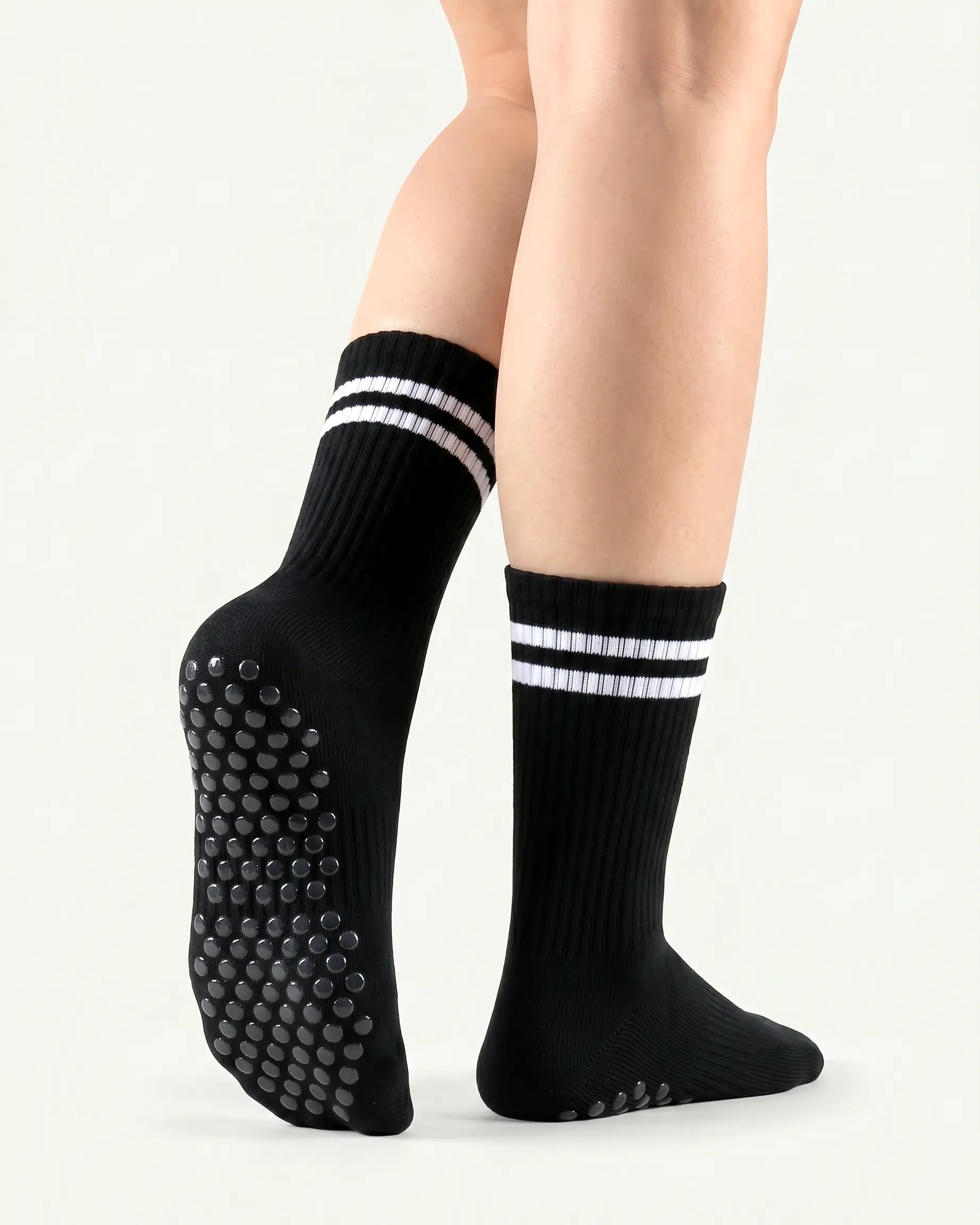 black | 02 | Black double-stripe crew grip socks back view showing sole grip pattern, ribbed knit texture, and stripe detail