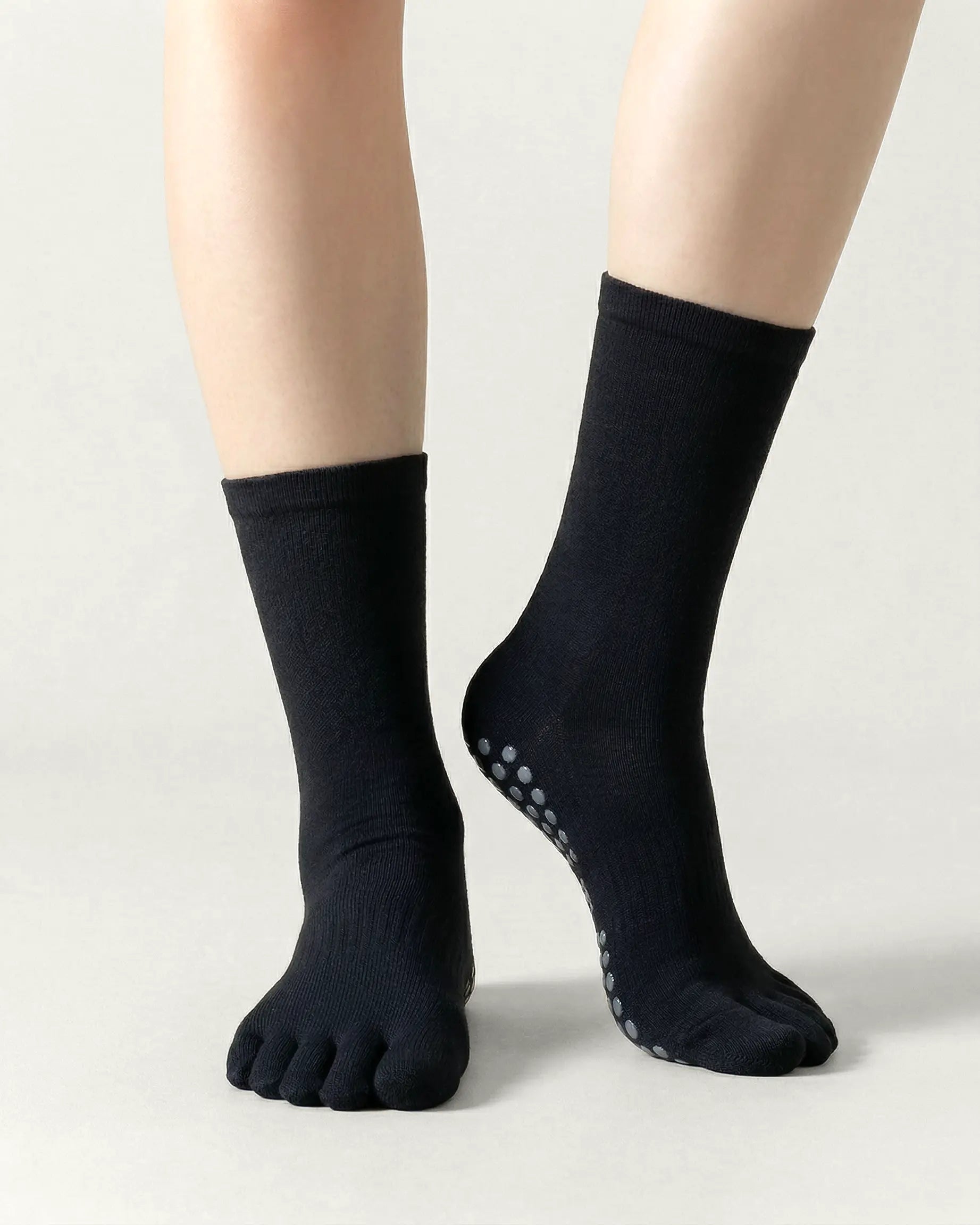 black | 04 | Black minimal five-toe grip socks front standing view showing toe separation, grip sole detail, and minimal silhouette