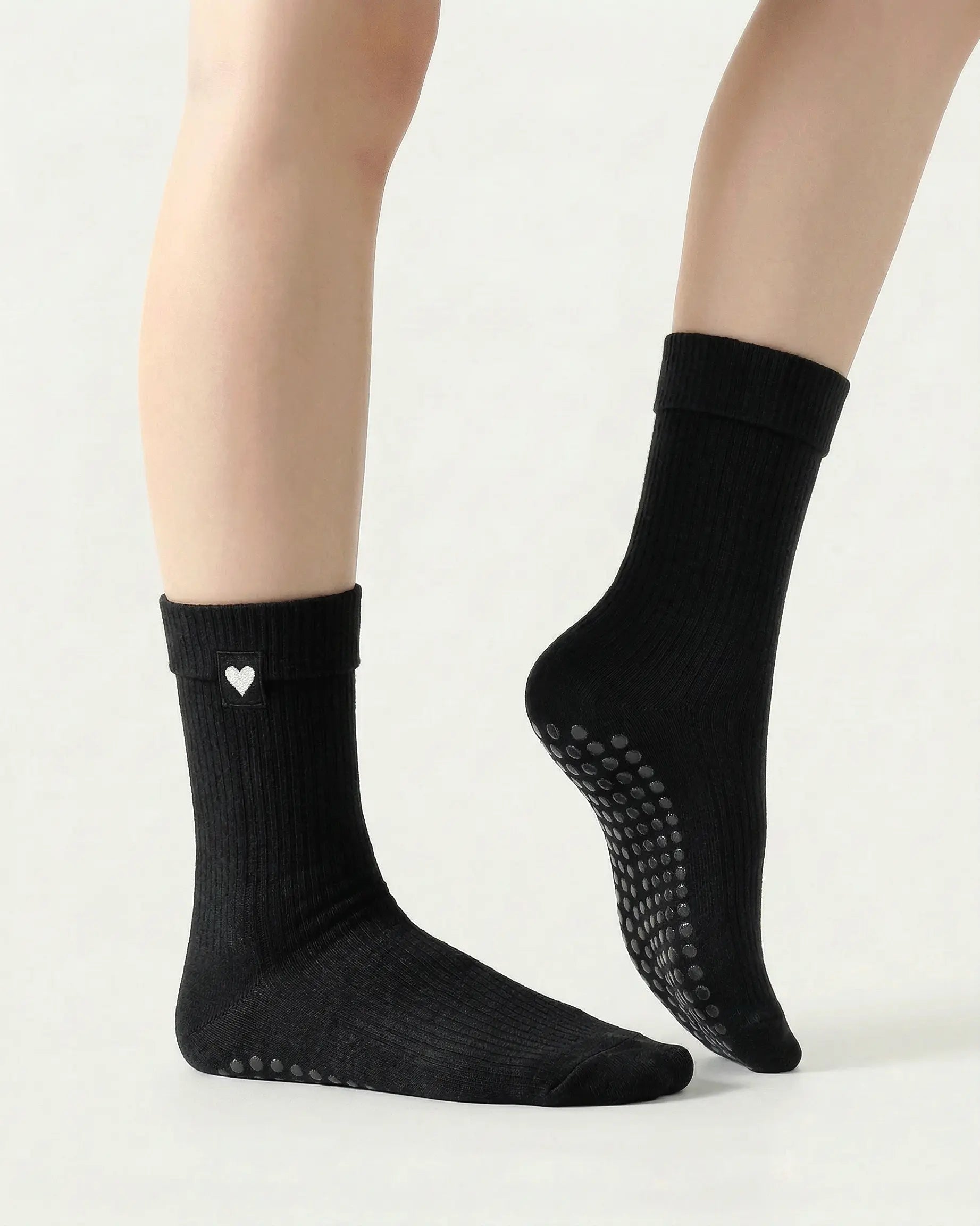 black | 03 | Black heart detail crew grip socks side pointed standing view showing crew length, ribbed texture, and minimal studio styling