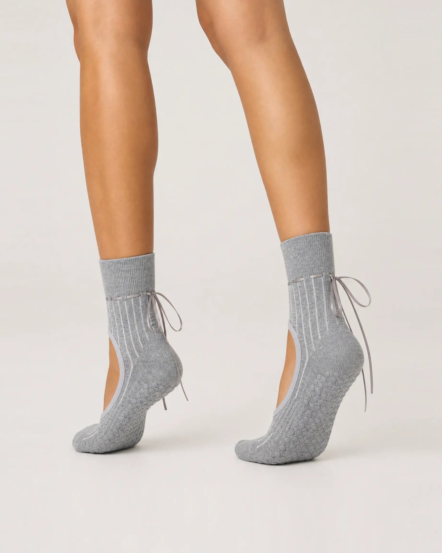 grey | 04 | Grey ribbon-tie open-instep grip socks side angled pointed standing view showing the covered heels, open insteps, and ribbon-tie details