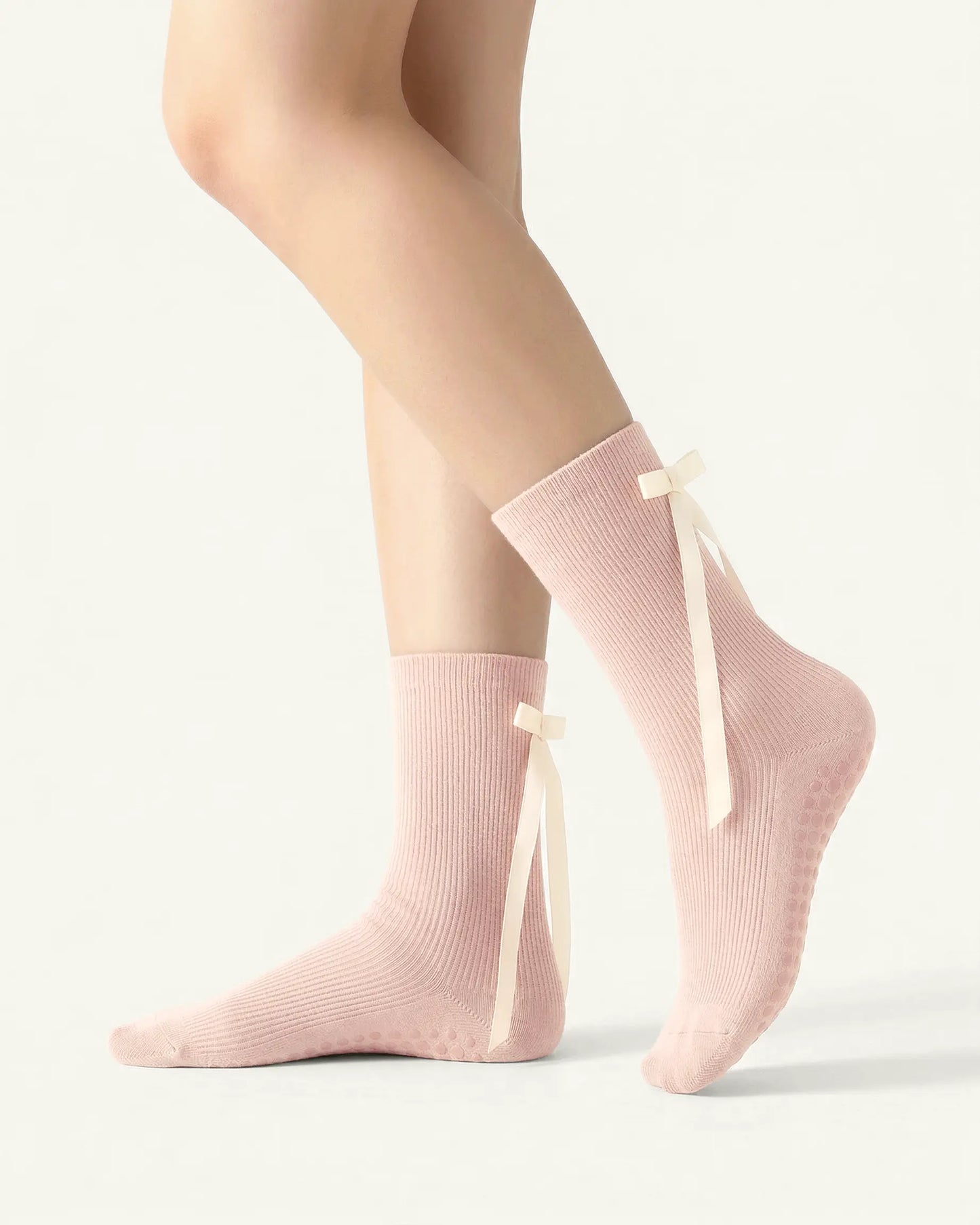 pink | 01 | Pink ballet ribbon crew grip socks side standing view showing ribbed knit texture, long ribbon bow detail, and ballet-inspired crew silhouette