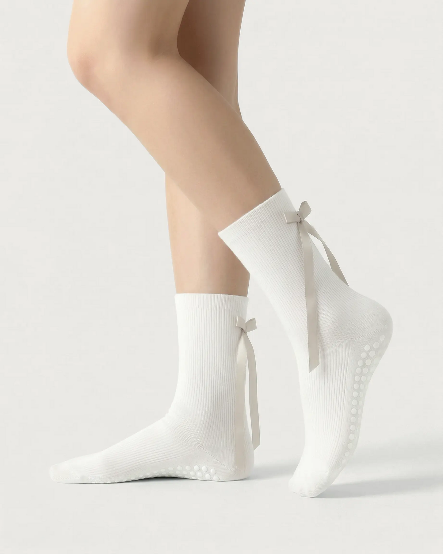 white | 01 | White ballet ribbon crew grip socks side standing view showing ribbed knit texture, long ribbon bow detail, and ballet-inspired crew silhouette