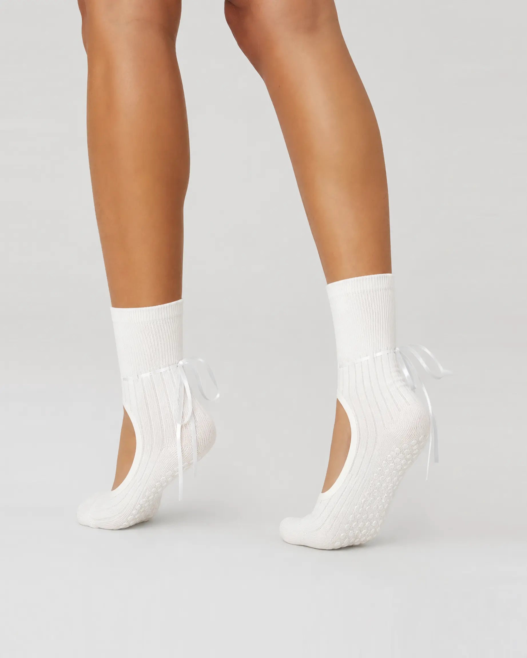 white | 04 | White ribbon-tie open-instep grip socks side angled pointed standing view showing the covered heels, open insteps, and ribbon-tie details